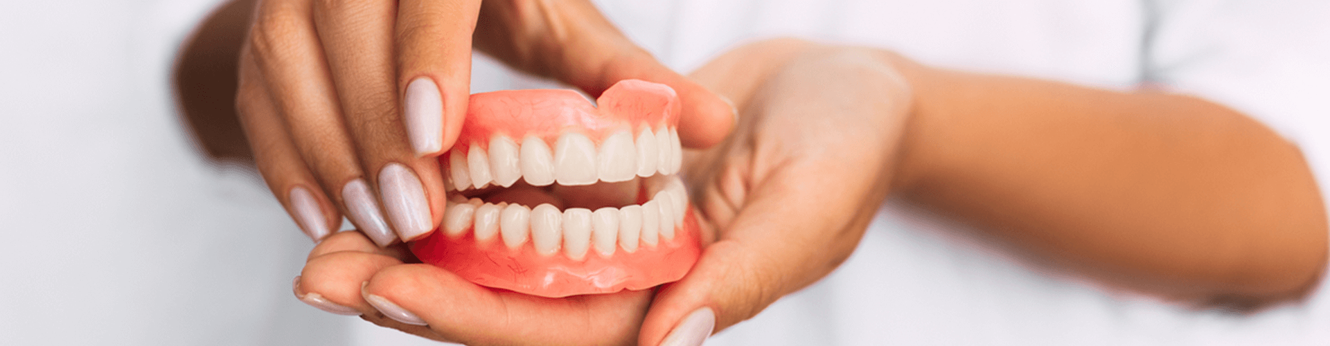 hands holding a pair of dentures
